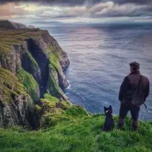 A dog and a man looking at Dunnesdrangar