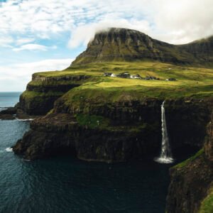 múlafossur waterfall, vágar, faroe islands waterfall falling straight off a cliff into the ocean in gásadalur, faroe islands
